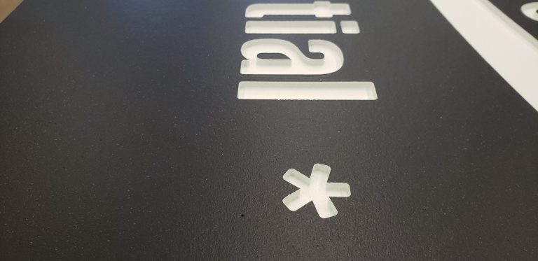 Past routed-and-painted HDU production: close-up of white recessed lettering and a dark painted face.