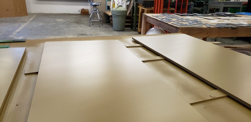 Painted PVC panels and backers laid out on shop tables.