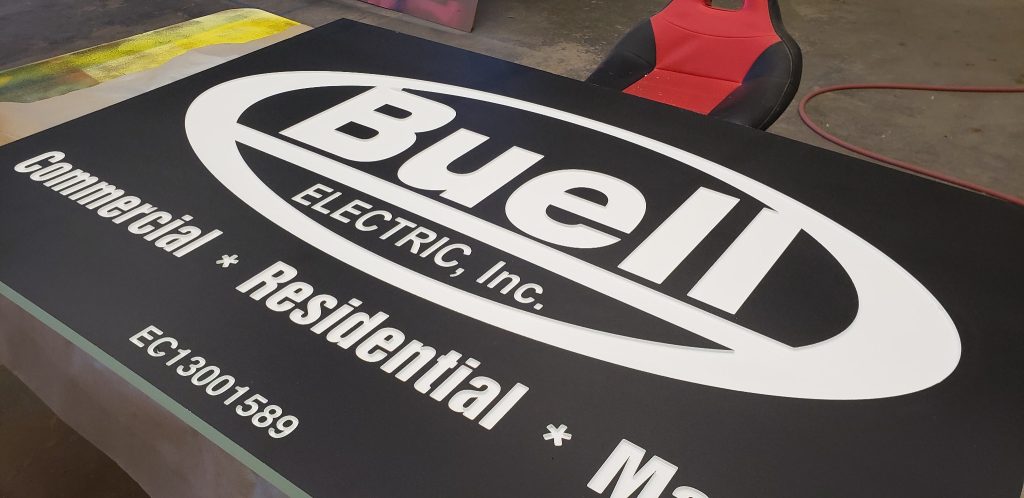 Routed HDU panel with white recessed lettering and a dark painted face.